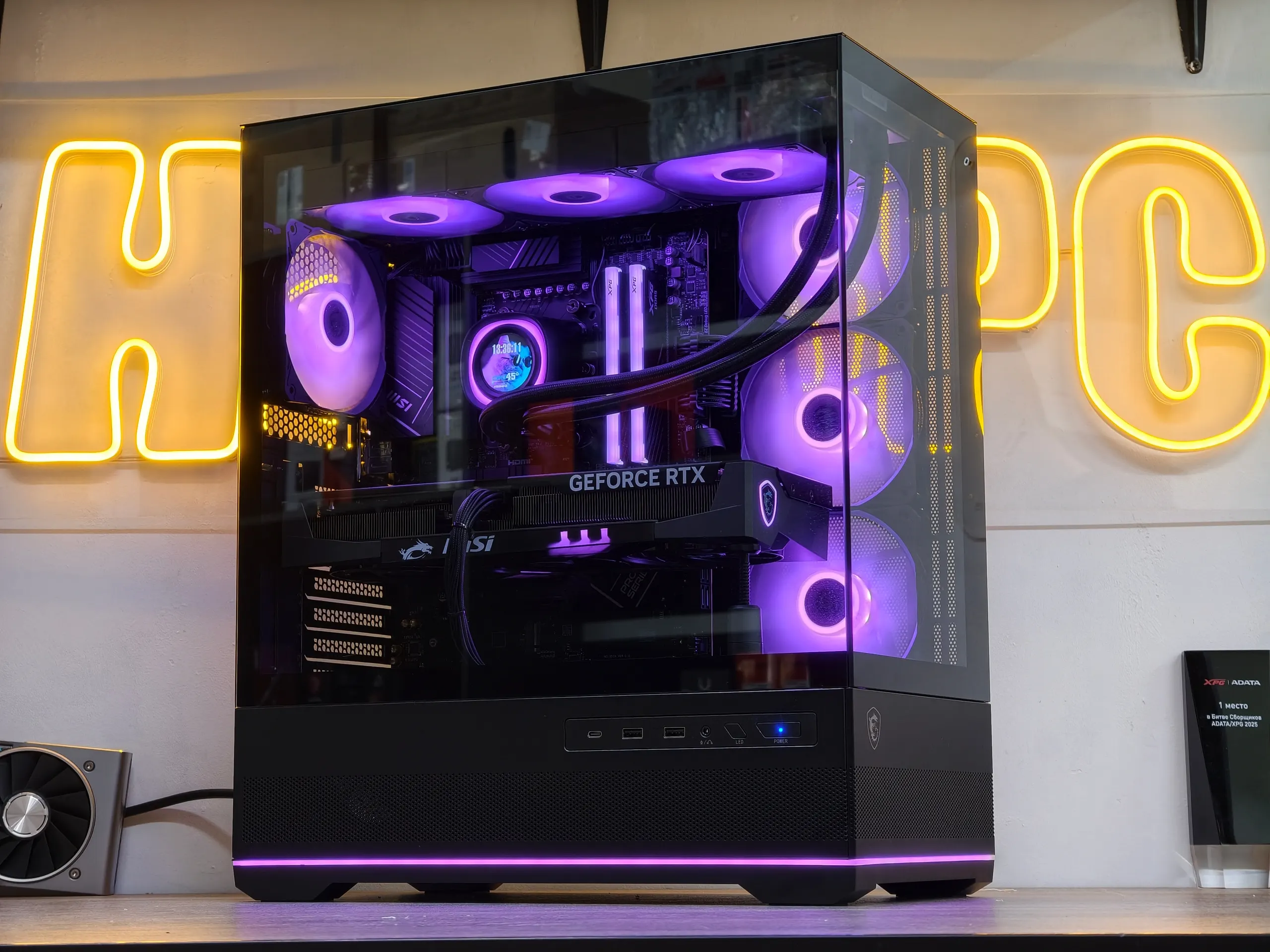 Игровая сборка с СЖО и фиолетовой подсветкой на фоне неоновой вывески HappyPC